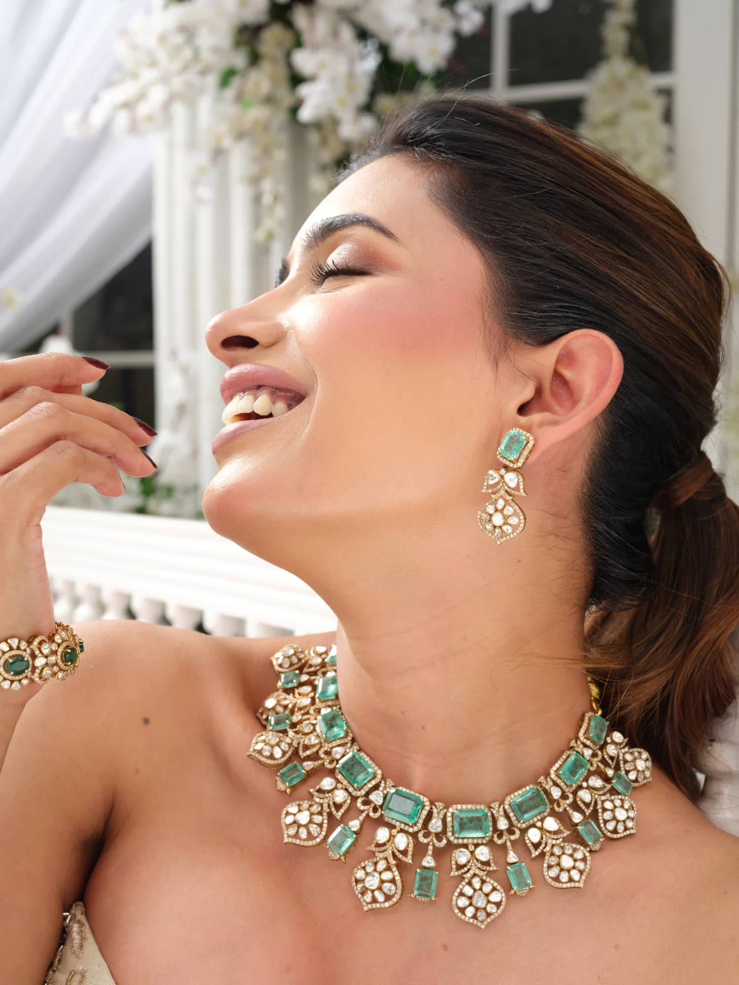 A model wearing the Inara open-polki choker with emerald-cut stones, matching drops and bracelet, in the blossom pavilion