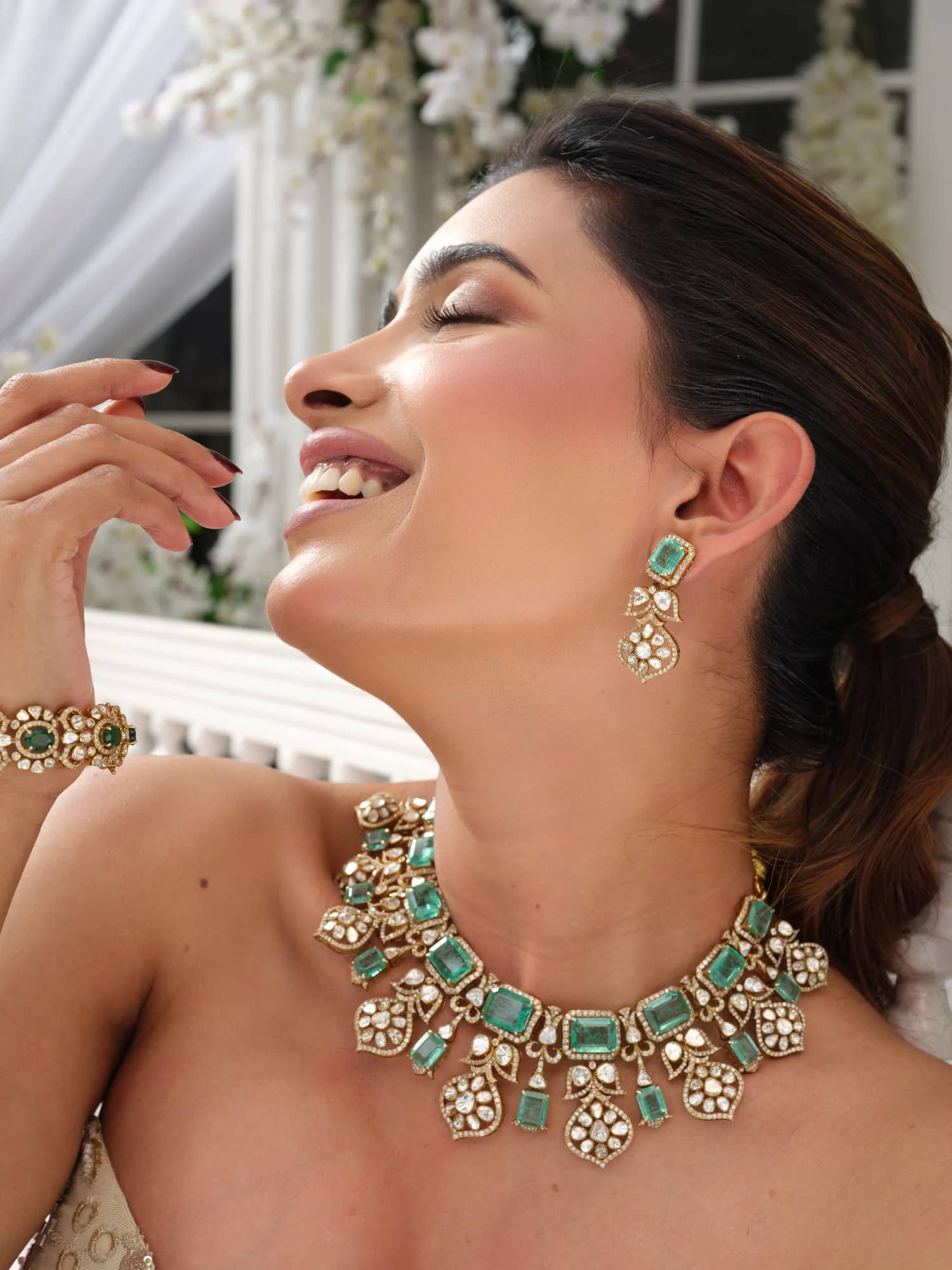 A model wearing the Inara open-polki choker with emerald-cut stones, matching drops and bracelet, in the blossom pavilion