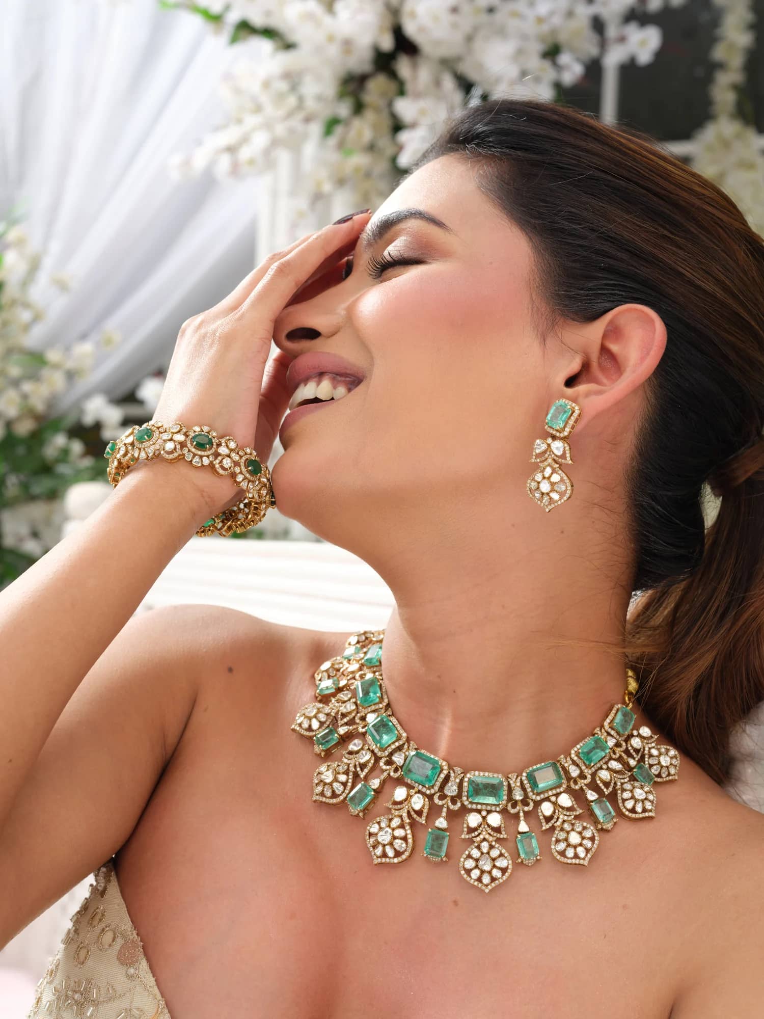 A model wearing the Inara open-polki choker with emerald-cut stones, matching drops and bracelet, in the blossom pavilion