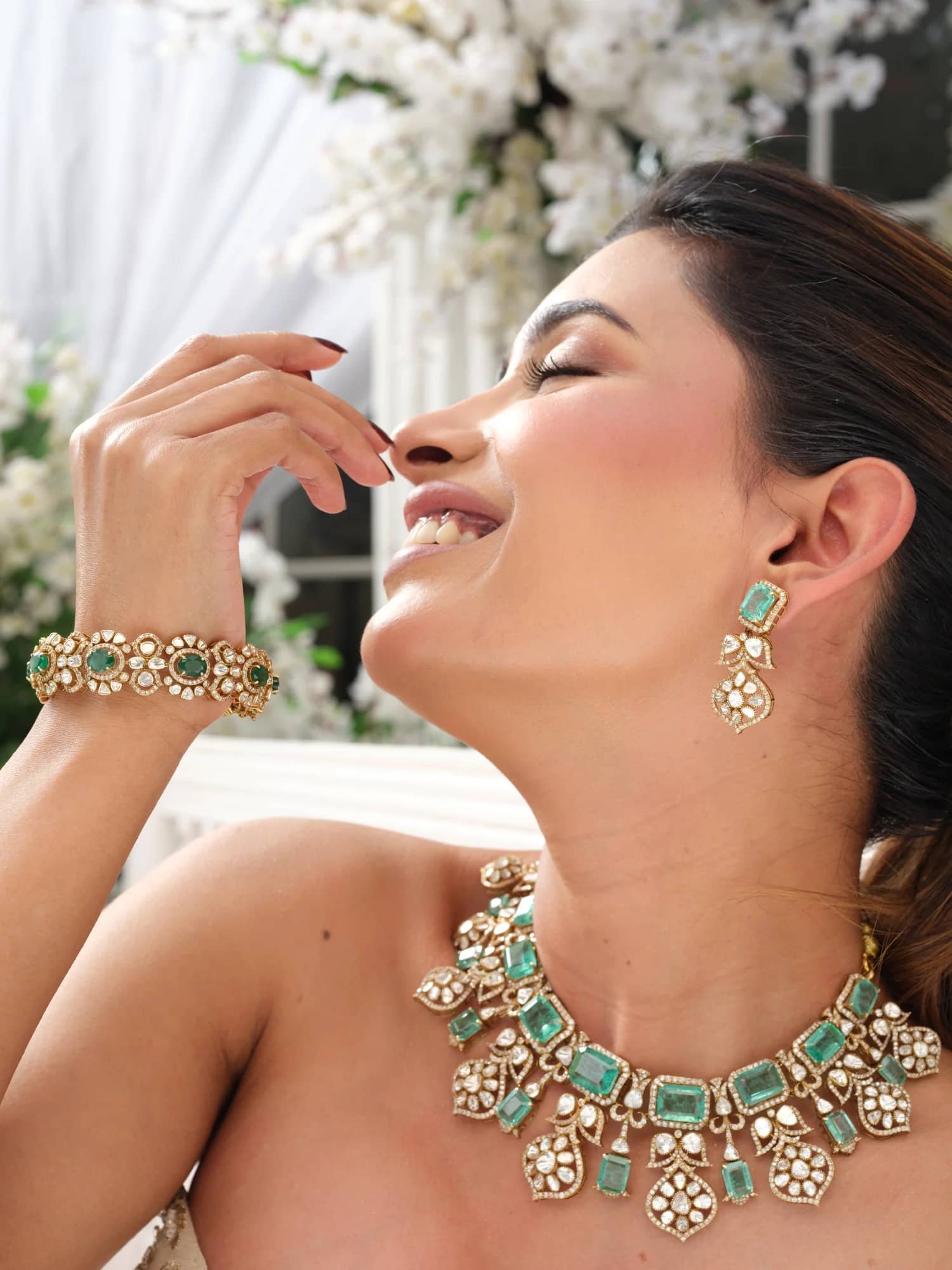 A model wearing the Inara open-polki choker with emerald-cut stones, matching drops and bracelet, in the blossom pavilion