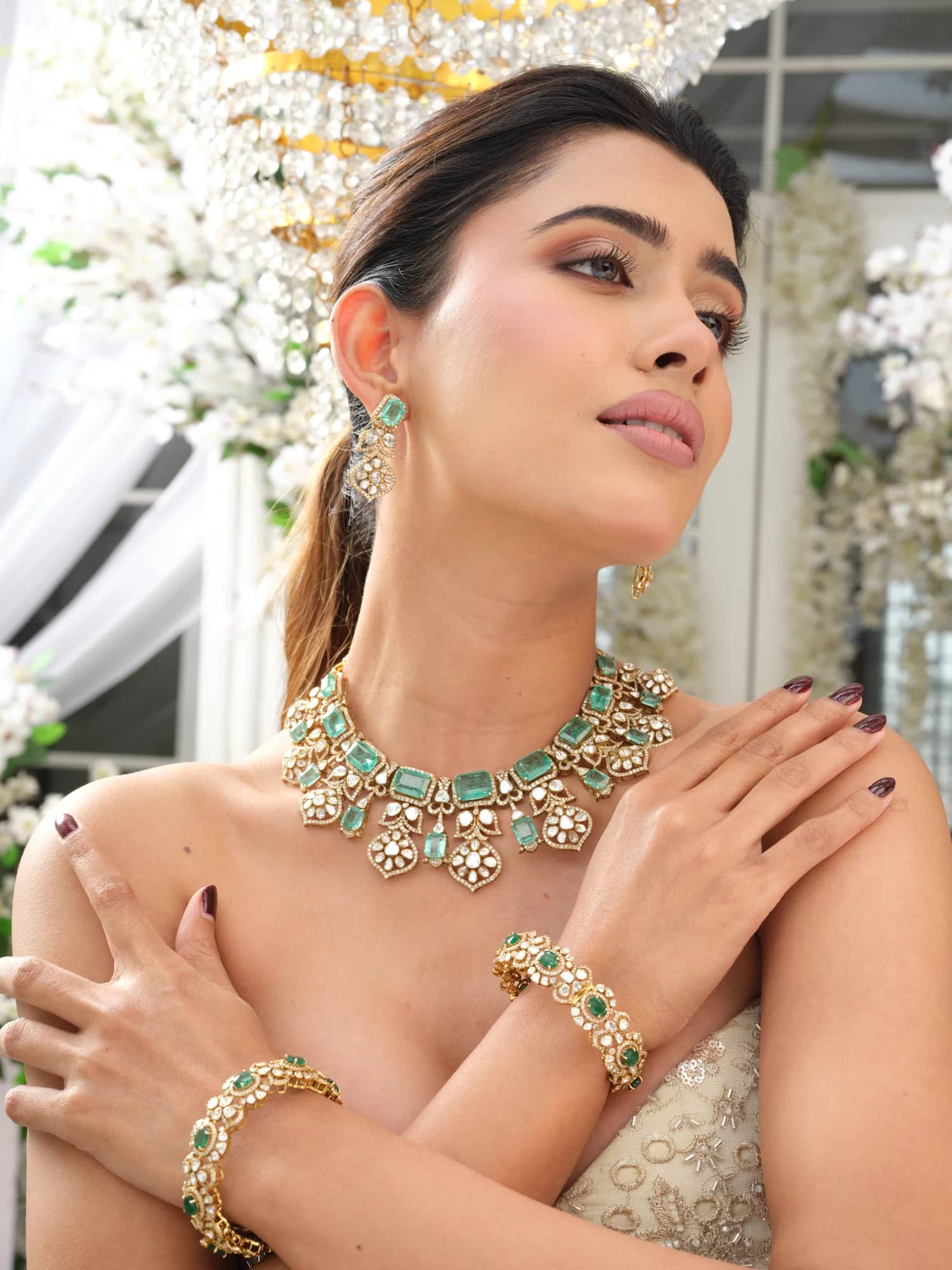 A model wearing the Inara open-polki choker with emerald-cut stones, matching drops and bracelet, in the blossom pavilion